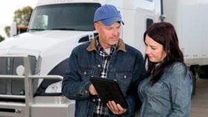 Truck driver and fleet manager reviewing Houston fleet management program on tablet
